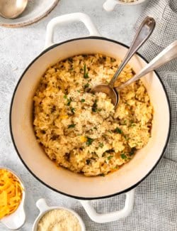 Pot of cheesy rice set next to small bowls of cheddar and Parmesan.