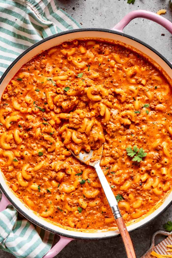 overhead photo of a pink pot of cheesy hamburger helper, with a spoon in it
