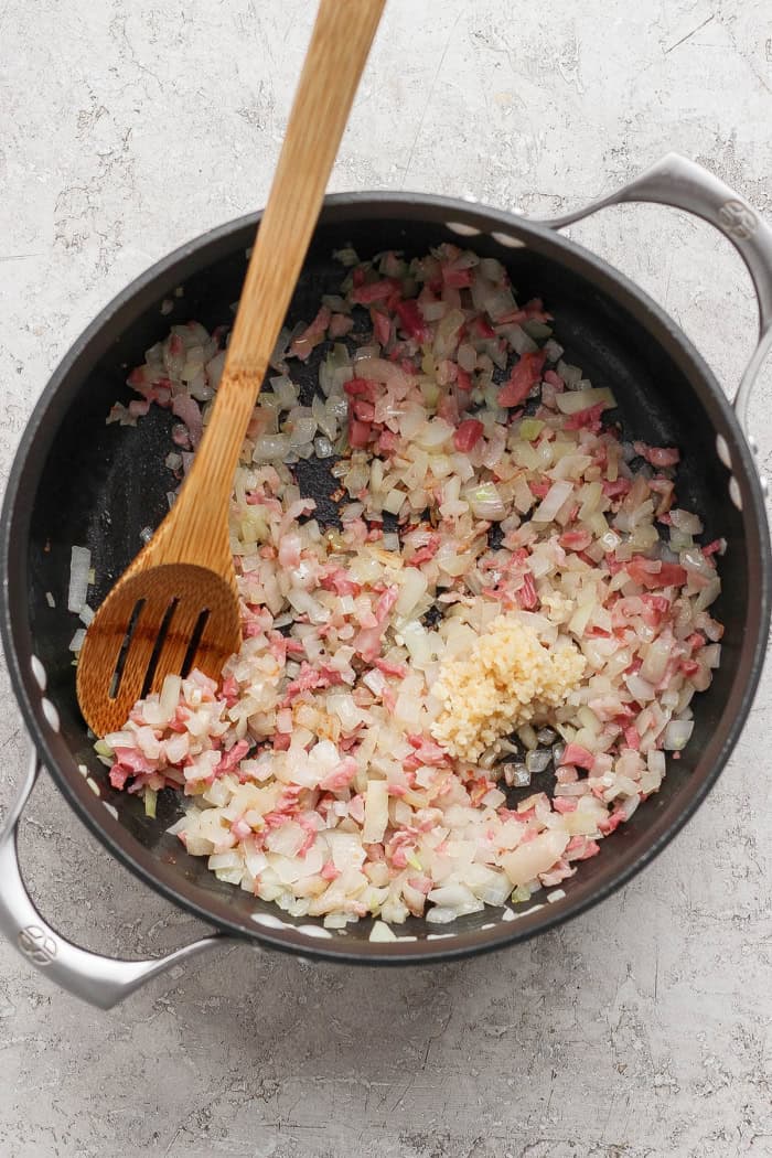 cooking pork belly, onion, and garlic in a black pot