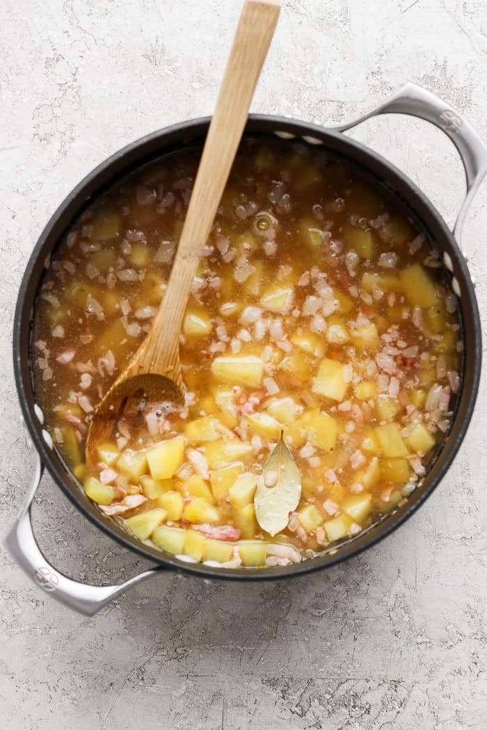 a large pot with onions, pork belly, potatoes, chicken broth, and clam juice