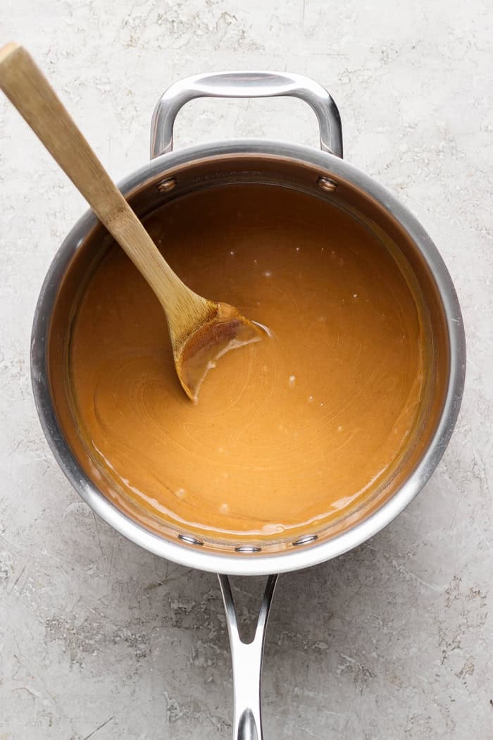 These scotcheroos are chewy, chocolatey, and peanut buttery, with a little sea salt to take them up a notch. An easy no-bake dessert recipe! Peanut butter mixture in saucepan with wooden spoon.