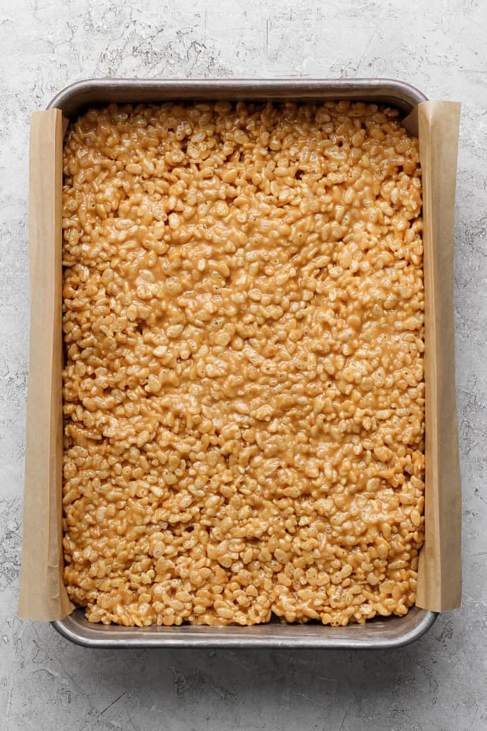 These scotcheroos are chewy, chocolatey, and peanut buttery, with a little sea salt to take them up a notch. An easy no-bake dessert recipe! Rice cereal layer for scotcheroos in pan.