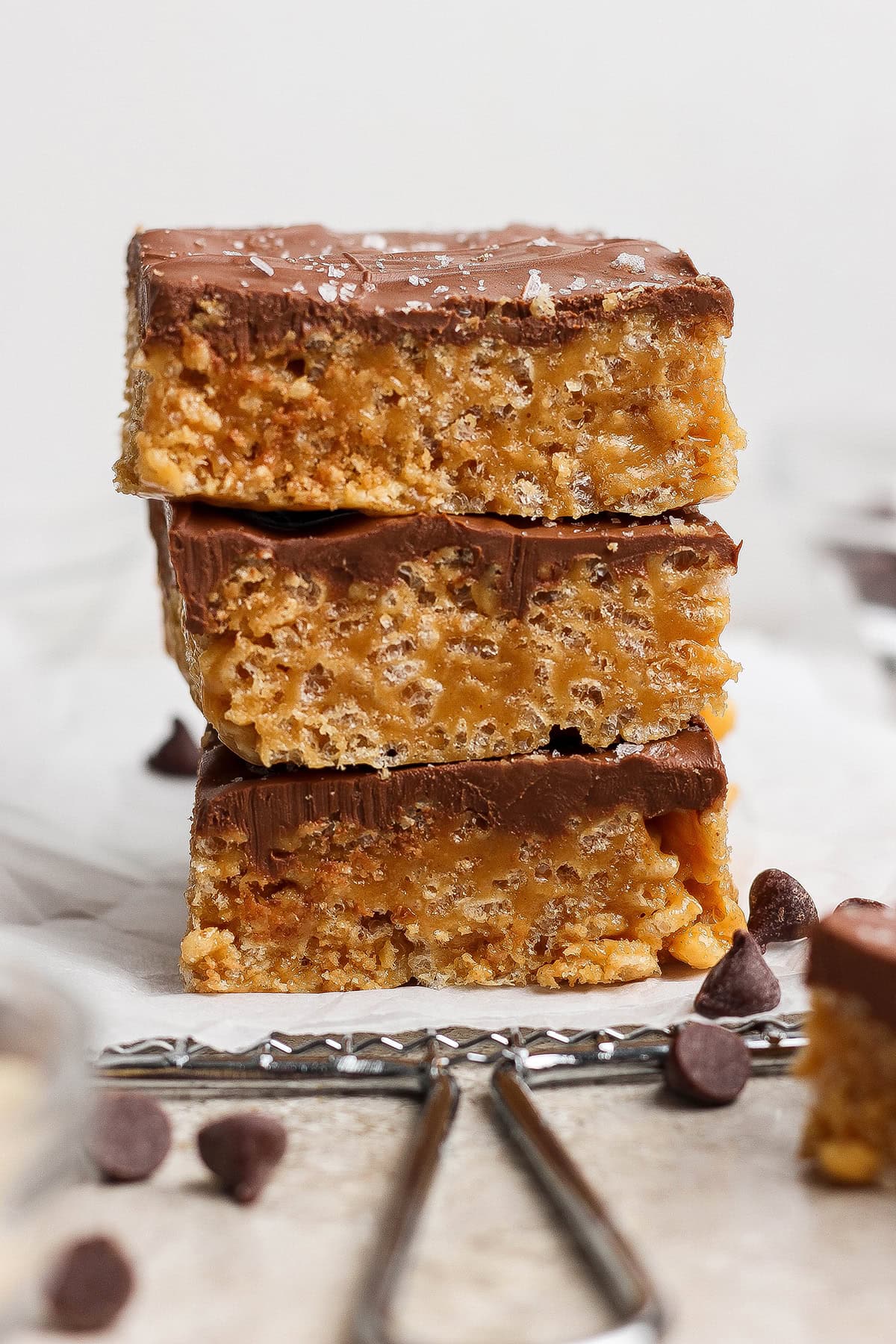 These scotcheroos are chewy, chocolatey, and peanut buttery, with a little sea salt to take them up a notch. An easy no-bake dessert recipe! Stack of 3 scotcheroos on parchment paper.