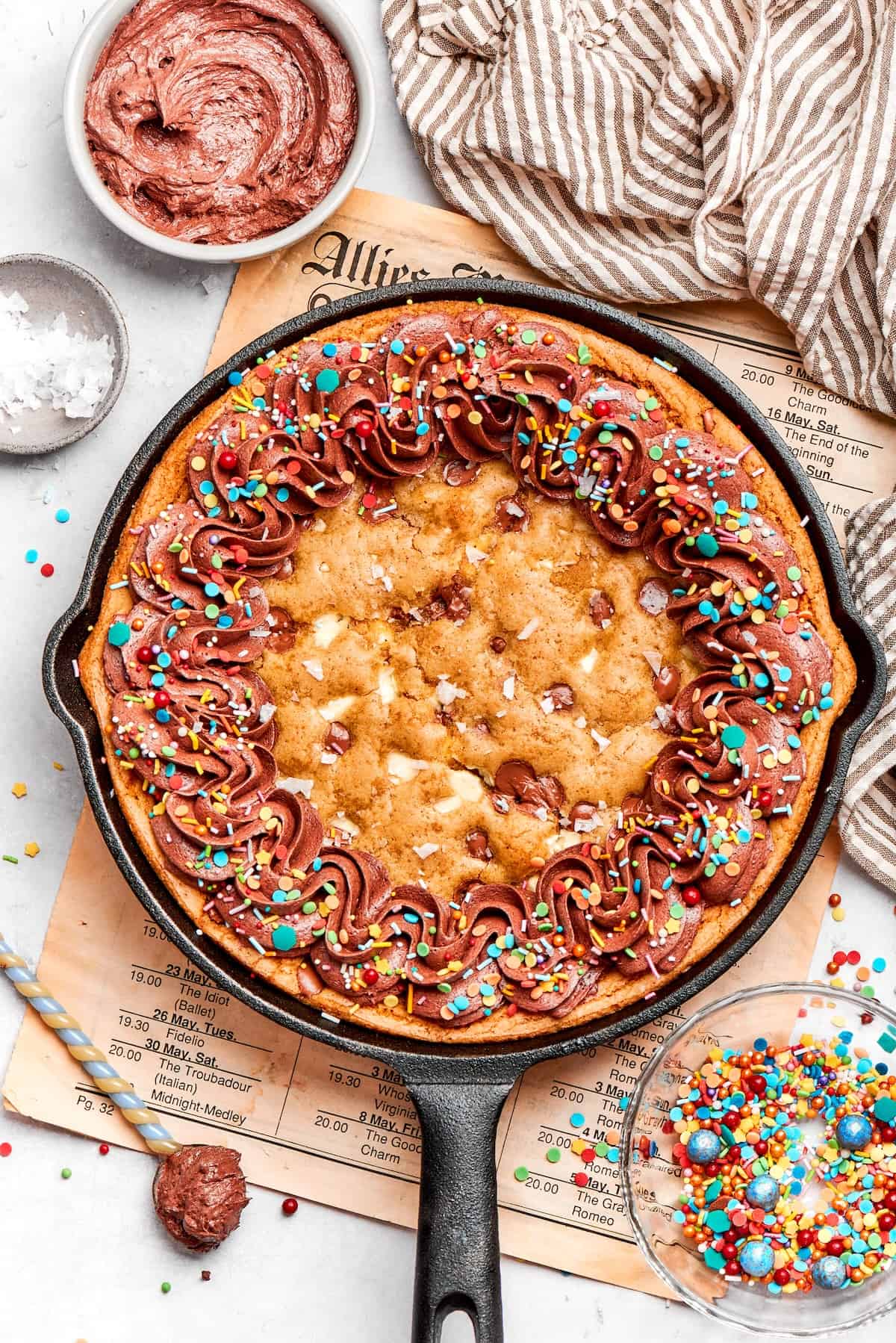 overhead photo of chocolate chip skillet cookie decorated with chocolate frosting and colorful sprinkles