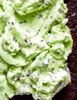 close-up photo of spreading mint chocolate chip buttercream over chocolate cake