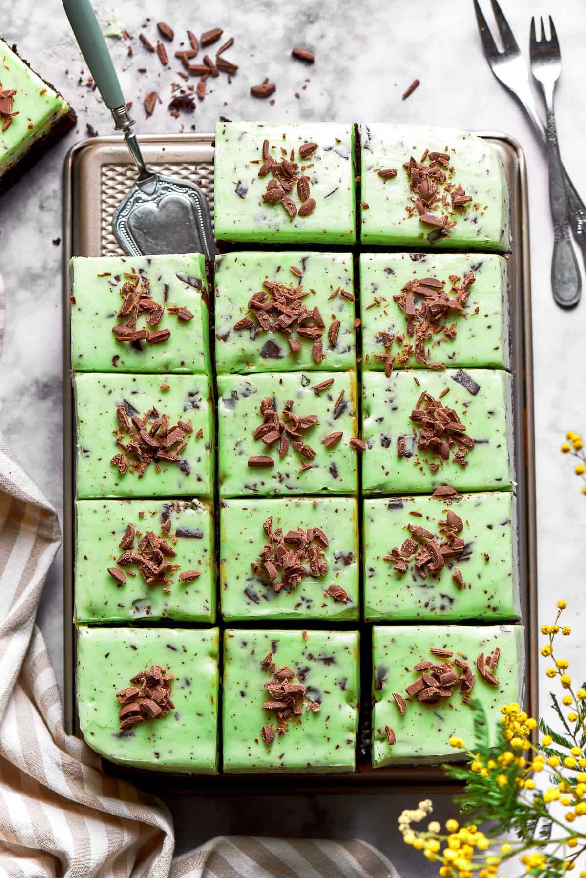 overhead photo of mint chocolate chip buttercream on cake that is cut into square pieces