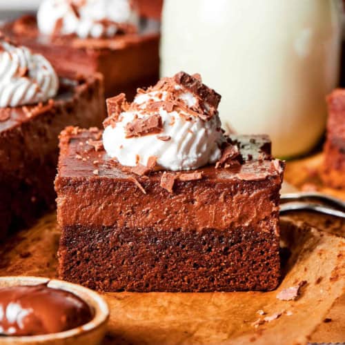 side view of a Nutella cheesecake bar with whipped cream and shaved chocolate on top