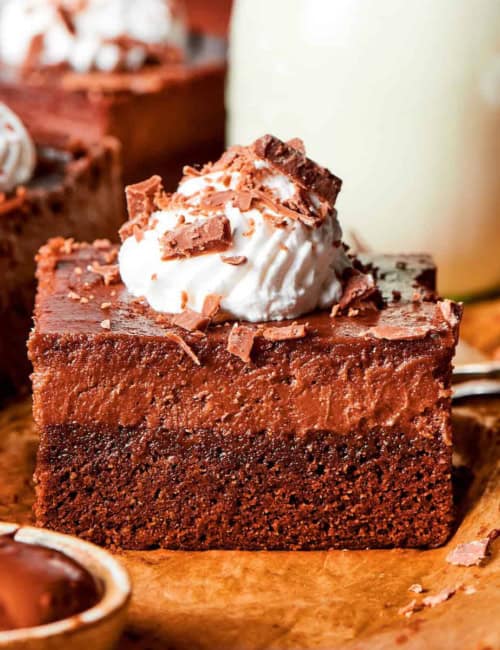 side view of a Nutella cheesecake bar with whipped cream and shaved chocolate on top