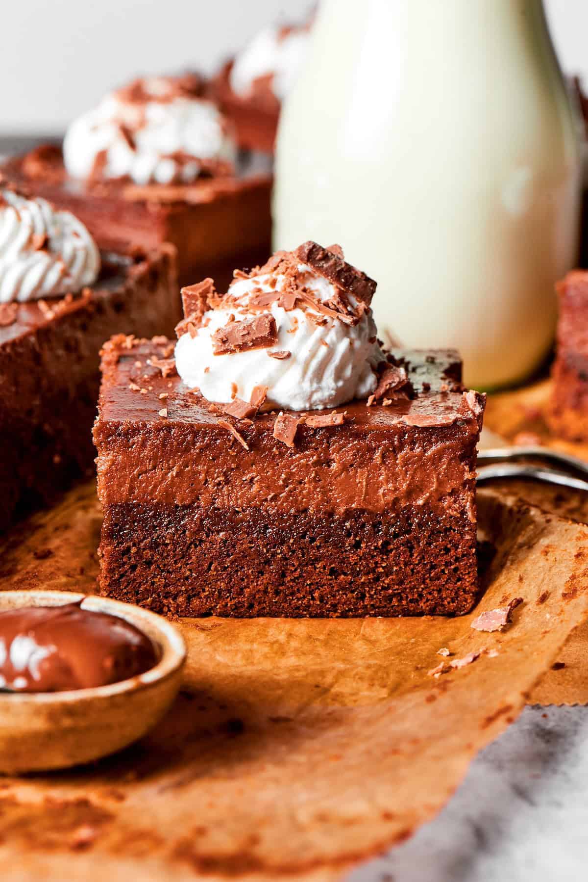 side view of a Nutella cheesecake bar with whipped cream and chocolate shavings on top