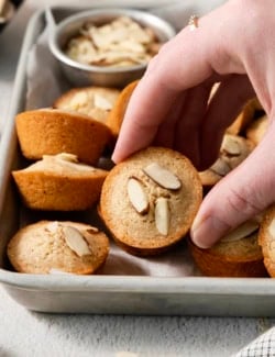 Hand picking up financiers from pan.