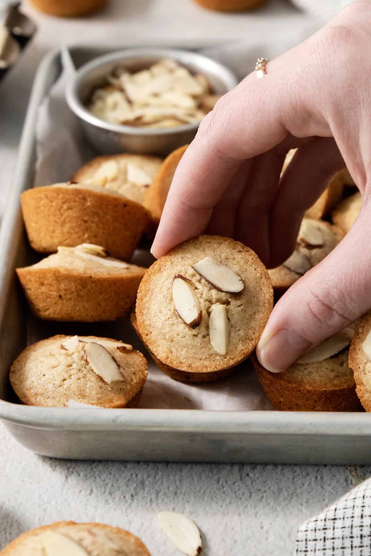 Hand picking up financiers from pan.