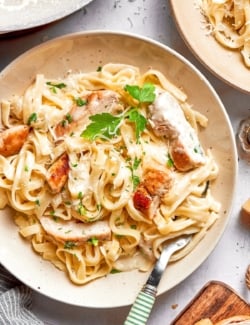 Chicken fettuccine alfredo in bowl with fork and parsley for garnish.