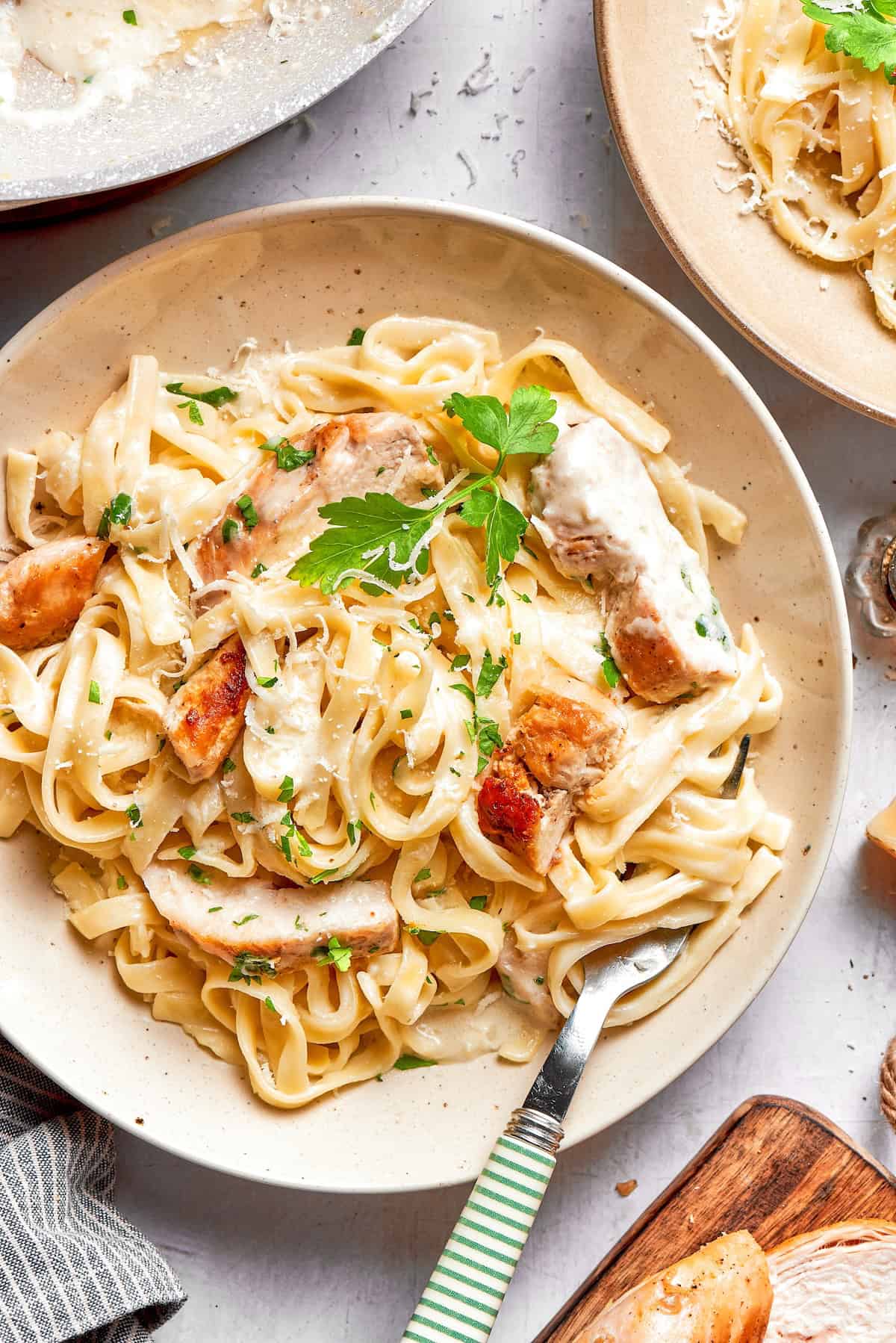 Chicken fettuccine alfredo in bowl with fork and parsley for garnish.