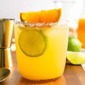 a glass of margarita cocktail, with fresh lime and orange