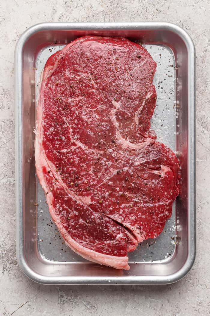 Seasoned steak on pan.