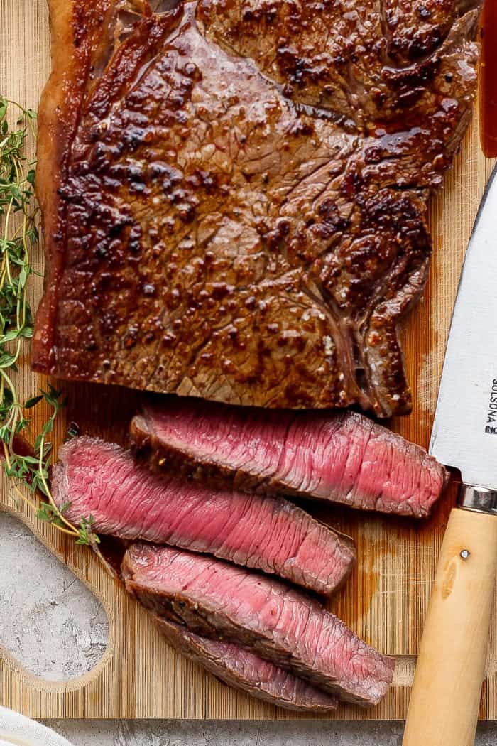 slicing steak on a wooden cutting board