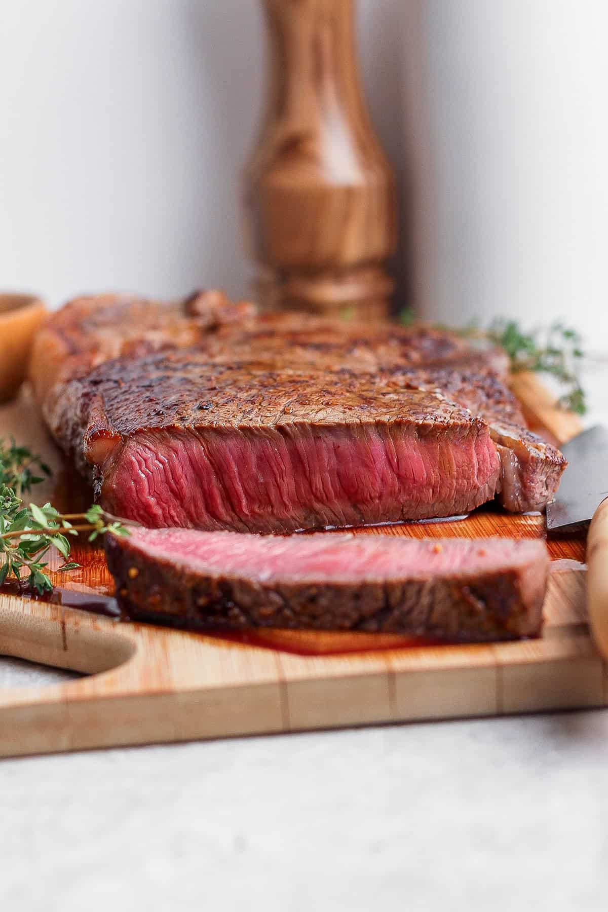 Cast iron skillet steak sliced on cutting board.
