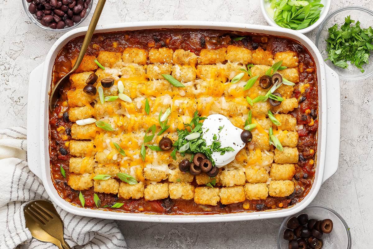 overhead photo of taco casserole with tater tots in a white 9 x 13 baking pan
