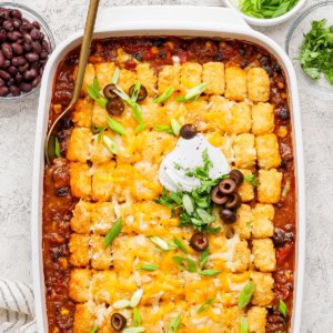 overhead photo of taco casserole with tater tots in a white 9 x 13 baking pan