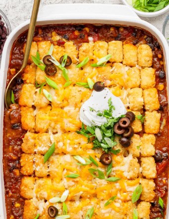 overhead photo of taco casserole with tater tots in a white 9 x 13 baking pan