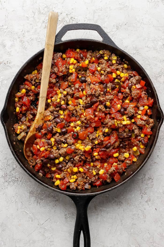 overhead photo of beef, tomatoes, black beans, and corn in a cast iron skillet