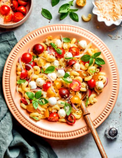 overhead photo of pasta caprese salad in a peach-colored serving bowl