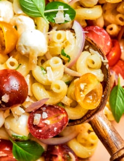 close-up photo of pasta caprese salad with a wooden spoon