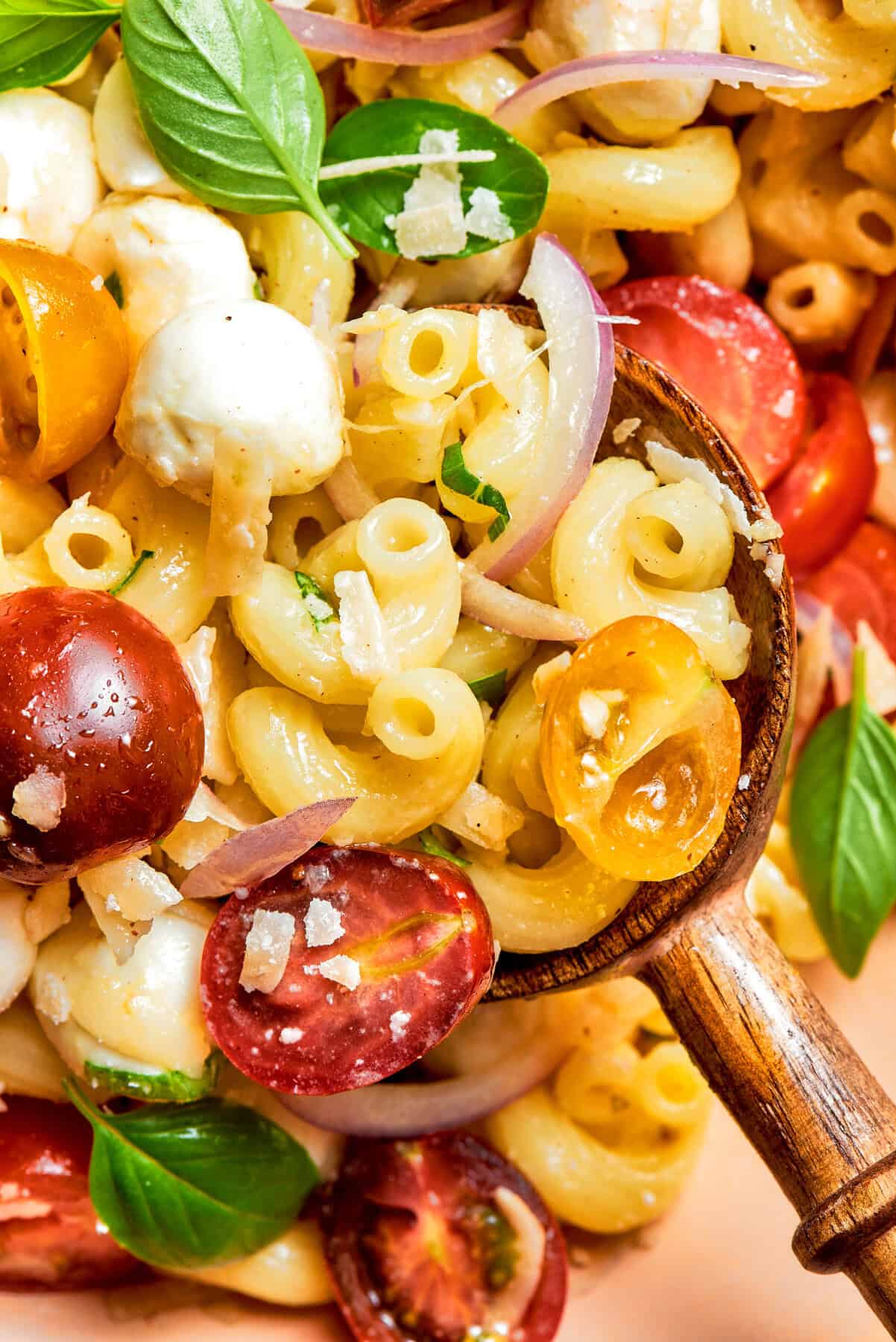 close-up photo of pasta caprese salad with a wooden spoon