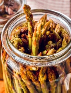 a jar of pickled asparagus, with a couple spears poking up out of the jar