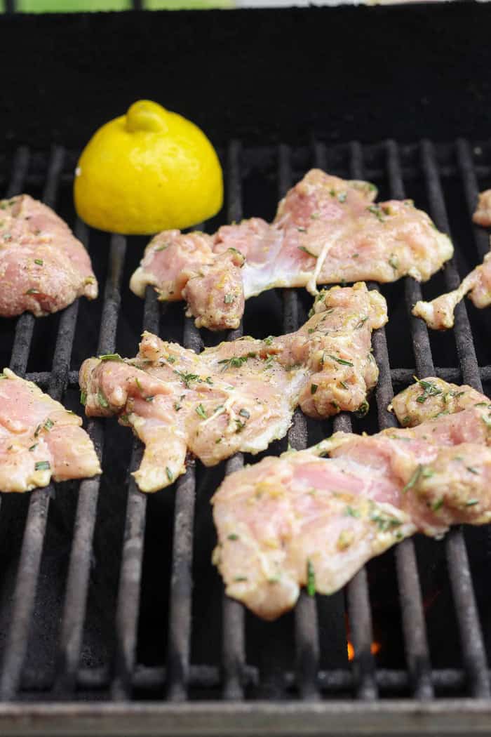 Marinated chicken thighs on grill.