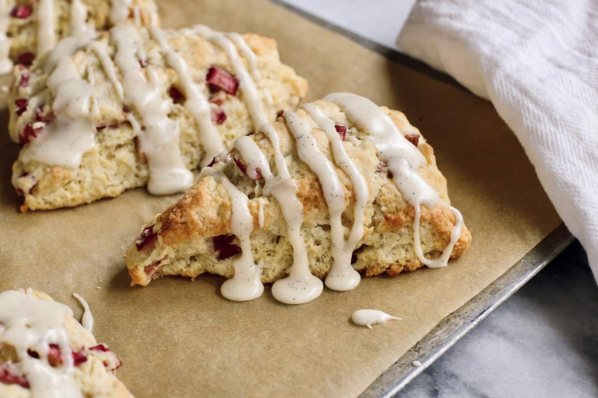 baked rhubarb scones with glaze, on a baking sheet with parchment paper