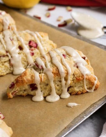 baked rhubarb scones with glaze, on a baking sheet with parchment paper