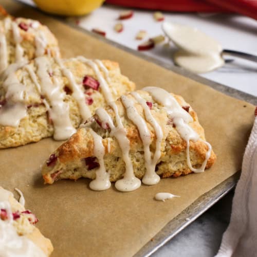 baked rhubarb scones with glaze, on a baking sheet with parchment paper