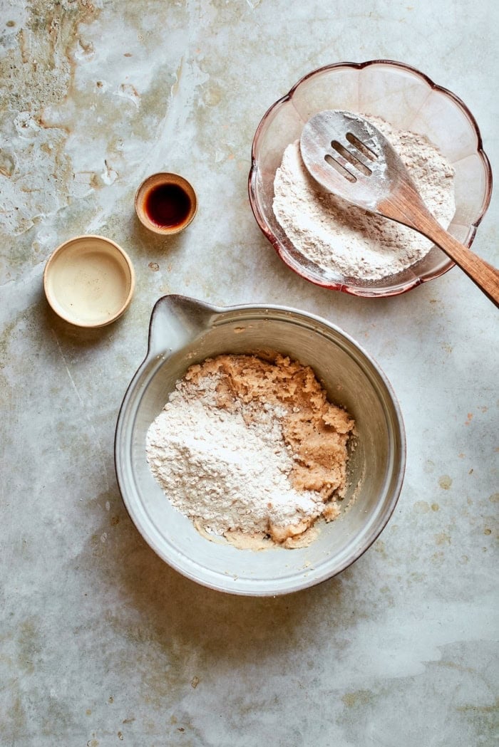 adding dry ingredients to creamed butter and sugar in a bowl