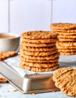 Two stacks of crispy oat cookies on pan.