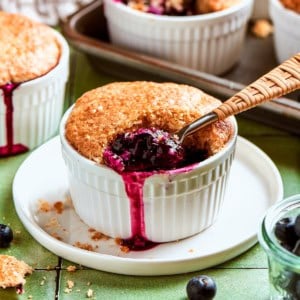mini blueberry cobbler in a ramekin, with a spoon digging into the blueberry filling
