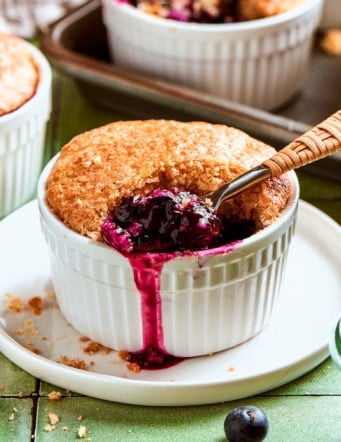 mini blueberry cobbler in a ramekin, with a spoon digging into the blueberry filling