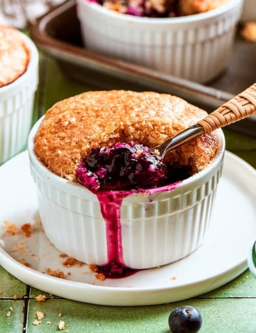 mini blueberry cobbler in a ramekin, with a spoon digging into the blueberry filling