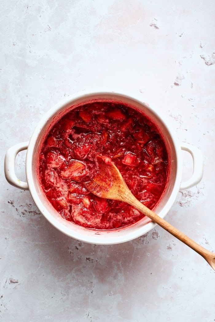 This homemade rhubarb ice cream is ultra creamy, with tart rhubarb flavor and a lovely blush-pink color. Such a fun summer dessert! Rhubarb cooking in pot.