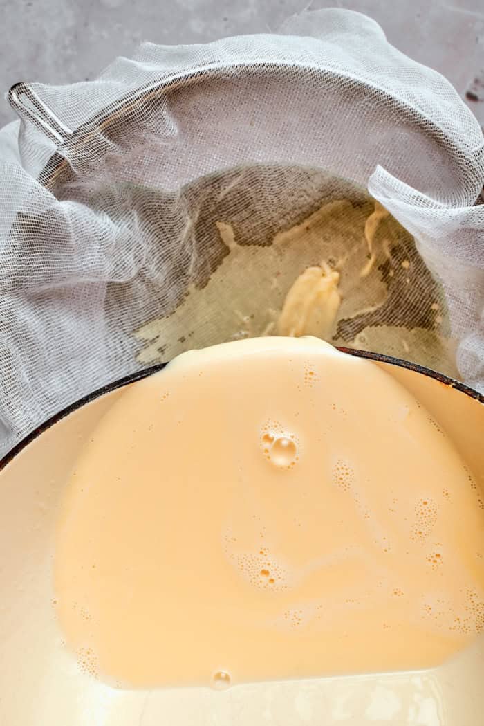 This homemade rhubarb ice cream is ultra creamy, with tart rhubarb flavor and a lovely blush-pink color. Such a fun summer dessert! Straining custard through cheesecloth.