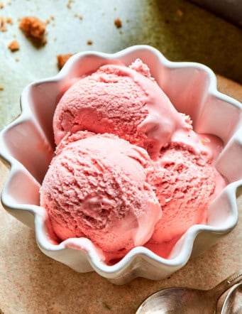 a small white fluted bowl with three scoops of pink rhubarb ice cream