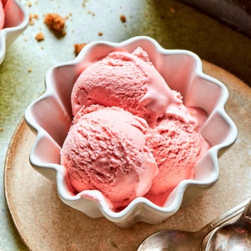 a small white fluted bowl with three scoops of pink rhubarb ice cream