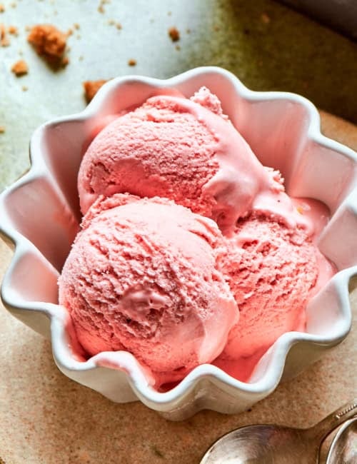 a small white fluted bowl with three scoops of pink rhubarb ice cream