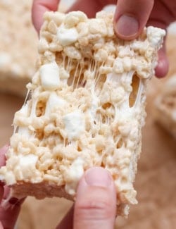 Hands pulling apart sticky brown butter rice krispie treat.