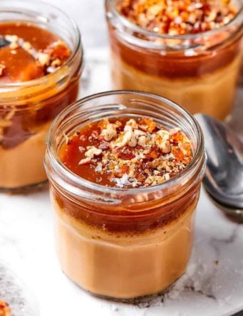 three small jars of caramel pots de creme with salted caramel sauce on top