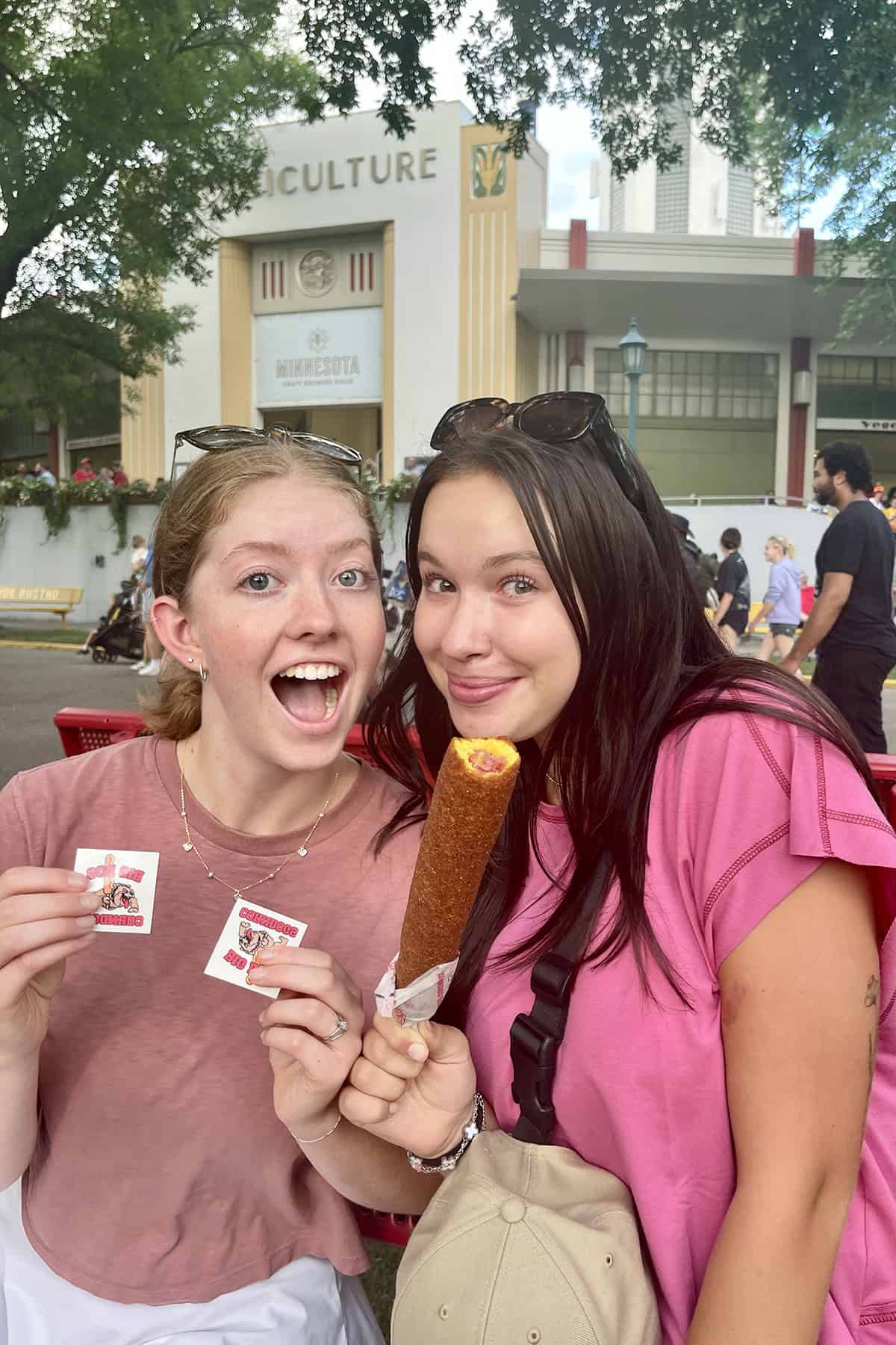 two girls sharing a corndog at the Minnesota State Fair