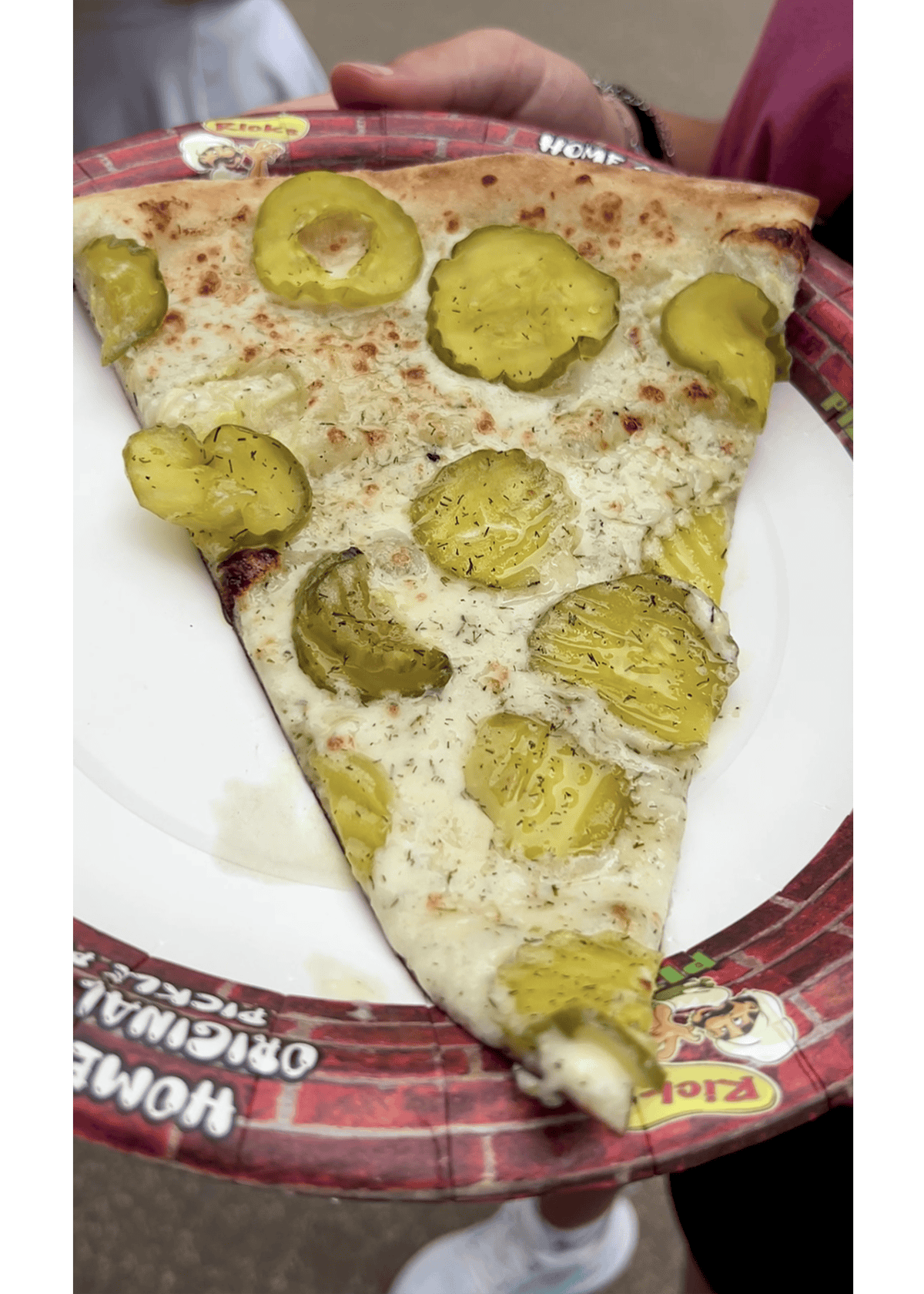 a large slice of pizza with dill pickle slices on top, at Minnesota State Fair