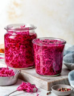 two jars of pickled red cabbage on a cutting board