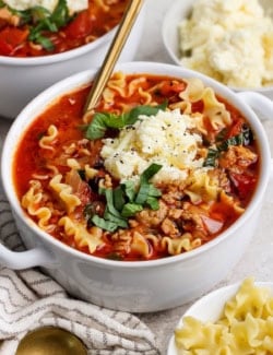 lasagna soup with dollop of cheesy yum and fresh basil on top, in white bowl