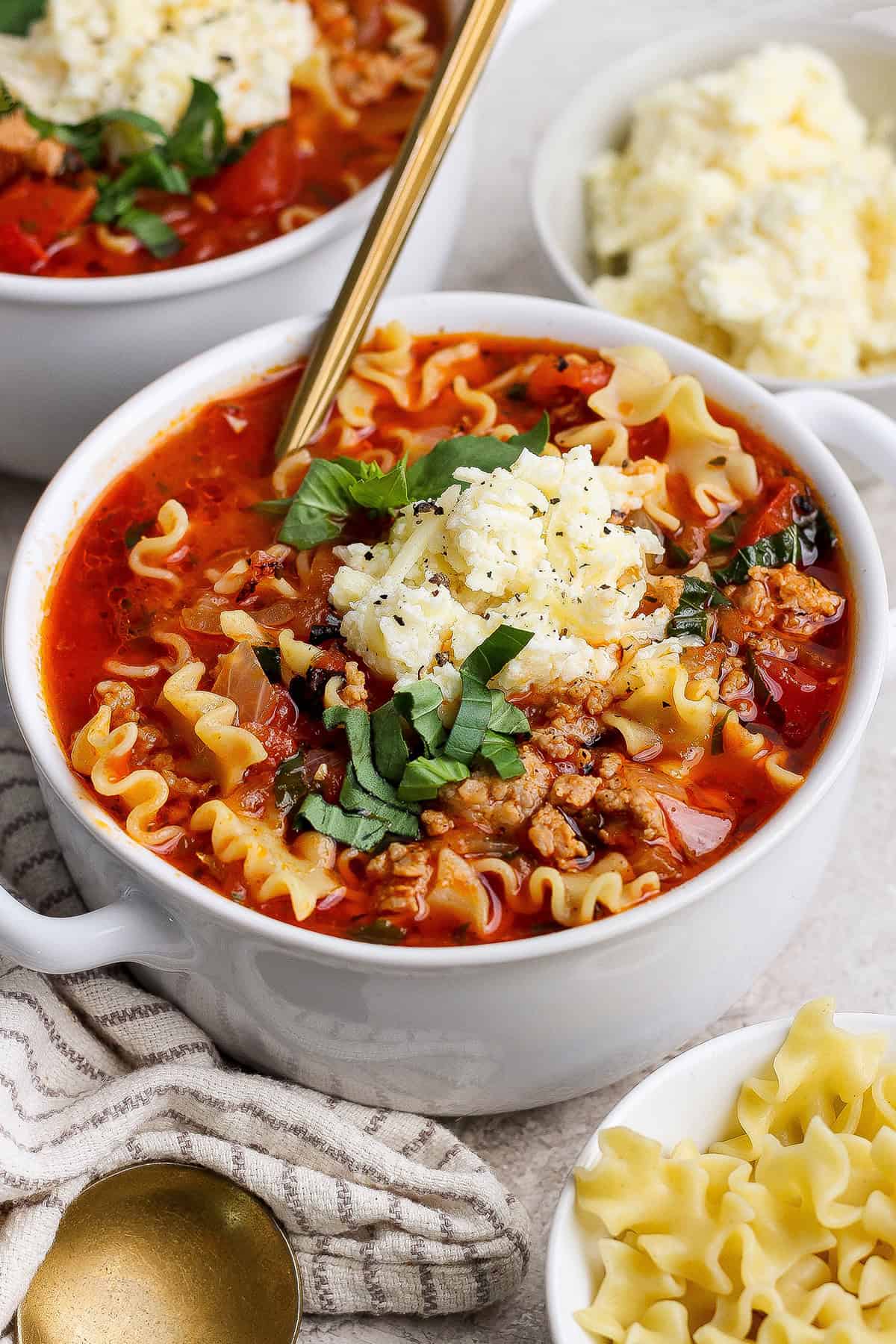 lasagna soup with dollop of cheesy yum and fresh basil on top, in white bowl